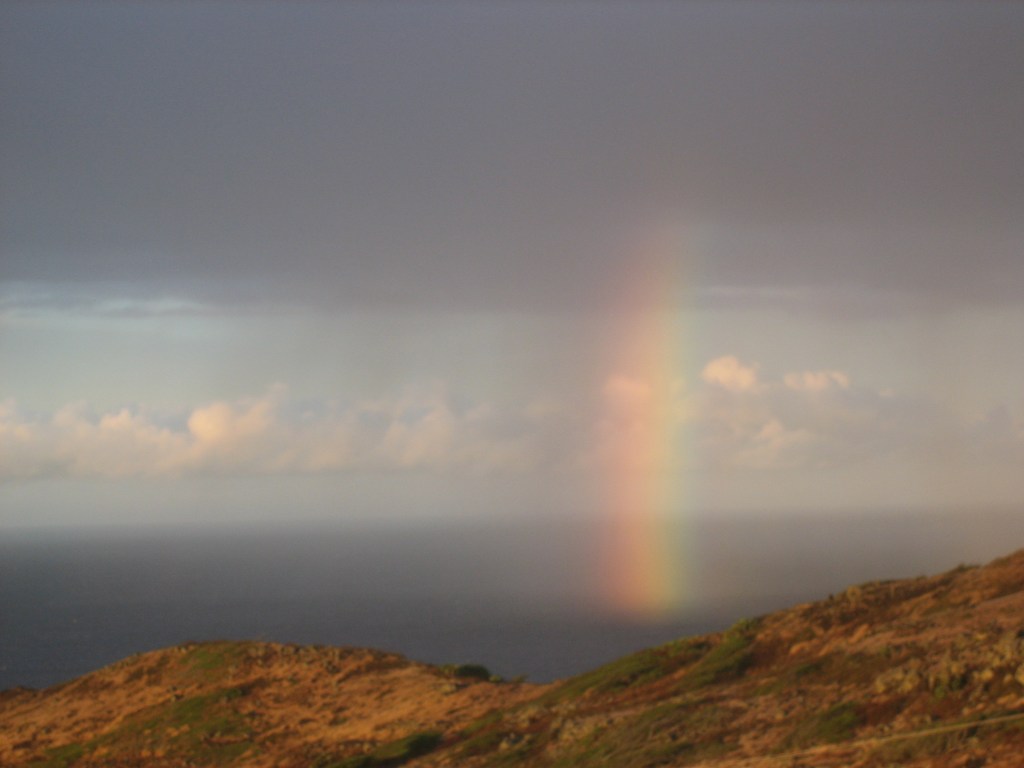 At the end of our sunrise hike, a rainbow dips into the Pacific Ocean off the coast of Hawaii